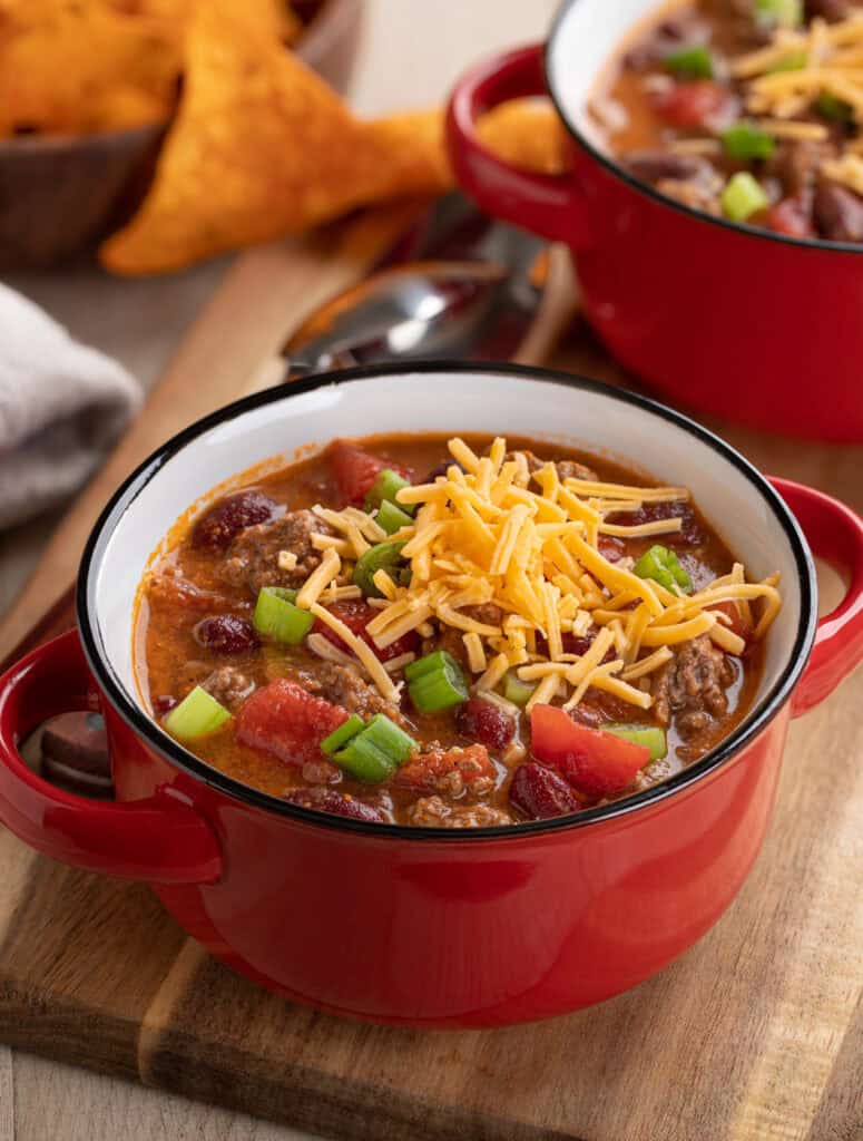 crock pot beef chili in a red bowl with cheese on top