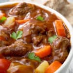 Crock pot beef stew in a white bowl with vegetables