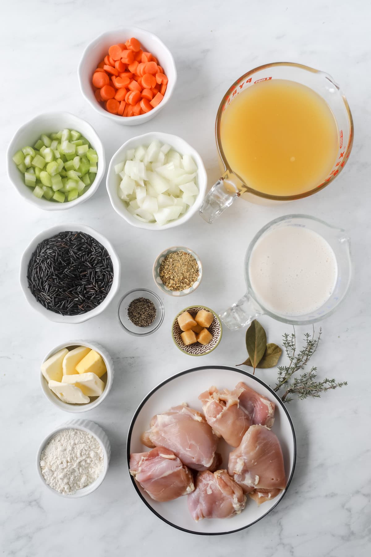 healthy chicken and wild rice soup ingredients for a slow cooker on a white marble counter