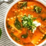 slow cooker lasagne soup in a white bowl with ricotta cheese and basil on top