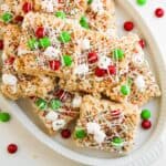 Red white and green Christmas Rice Krispies cut into squares and served on a white plate.