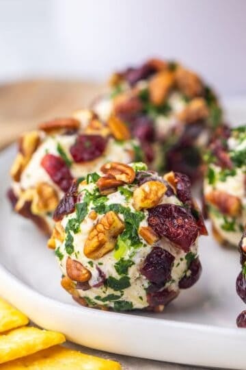 Cranberry and Pecan Mini Cheese Balls on a white plate with crackers to the side
