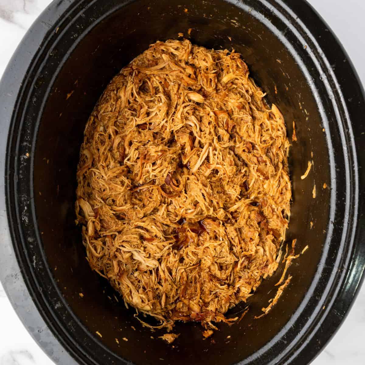slow cooked chicken in a sweet and savory honey garlic sauce sitting in the crockpot