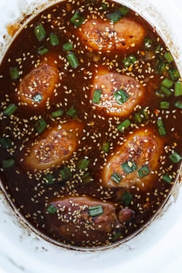 crock pot honey garlic chicken thighs in a white slow cooker