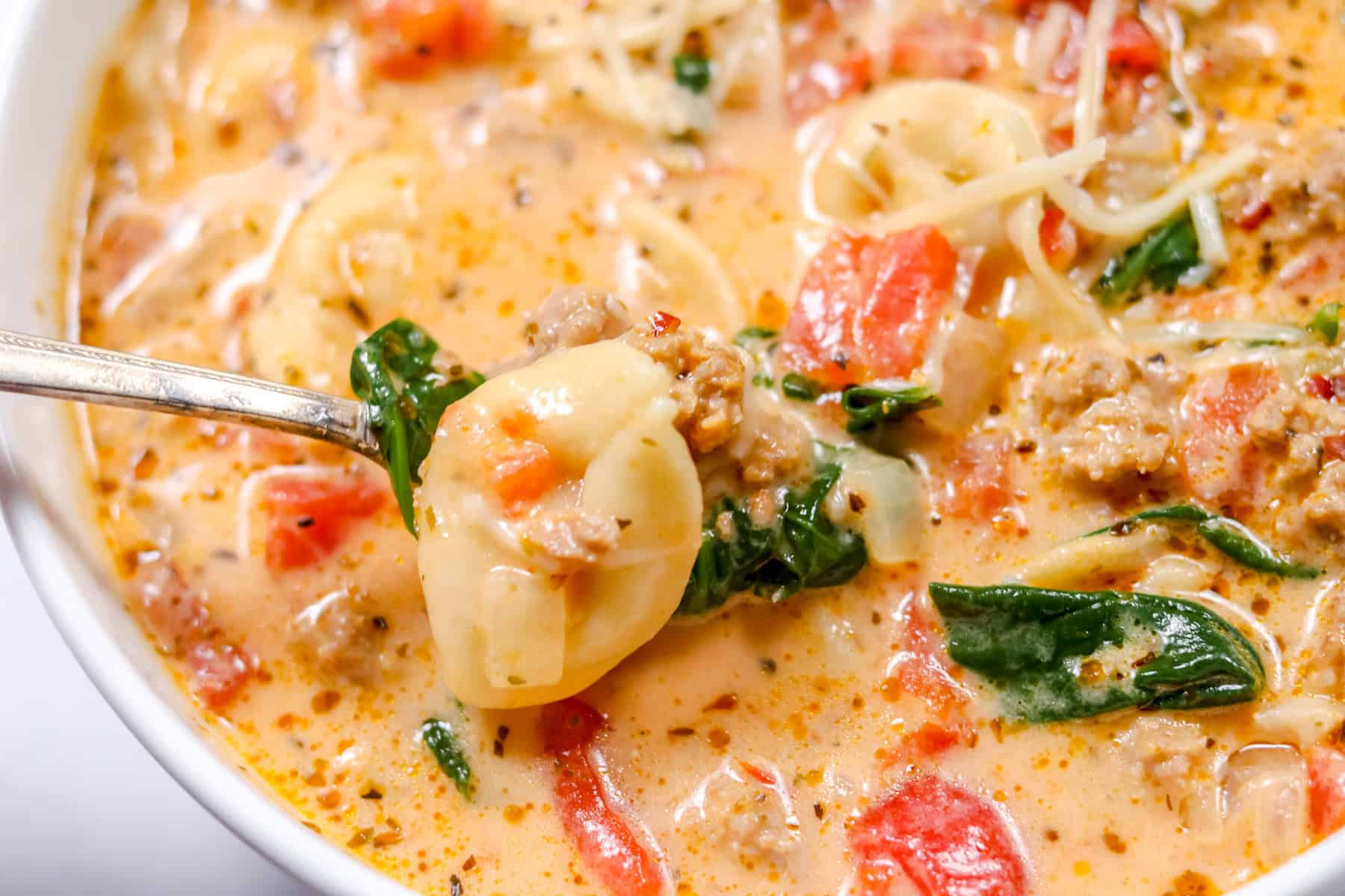 italian tortellini soup with sausage and spinach in a white bowl
