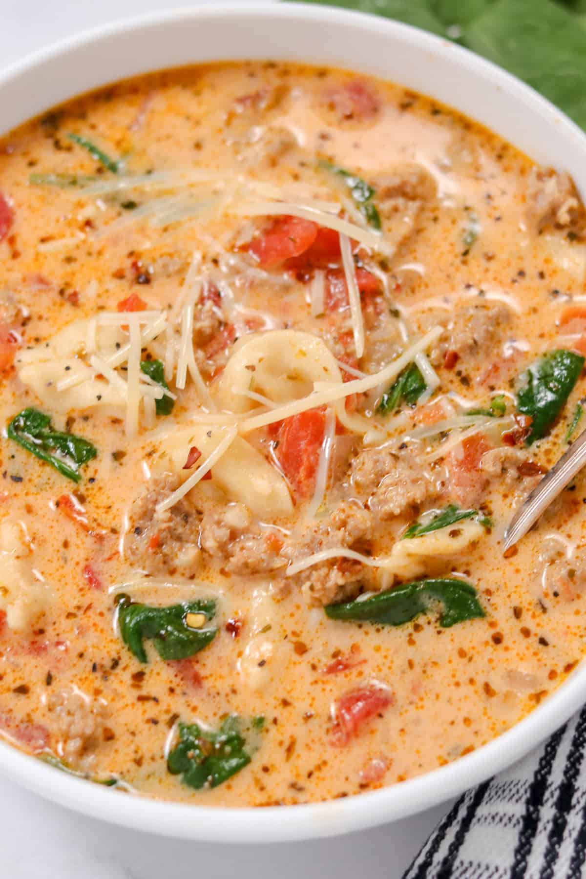 tortellini soup with sausage and spinach in a white bowl