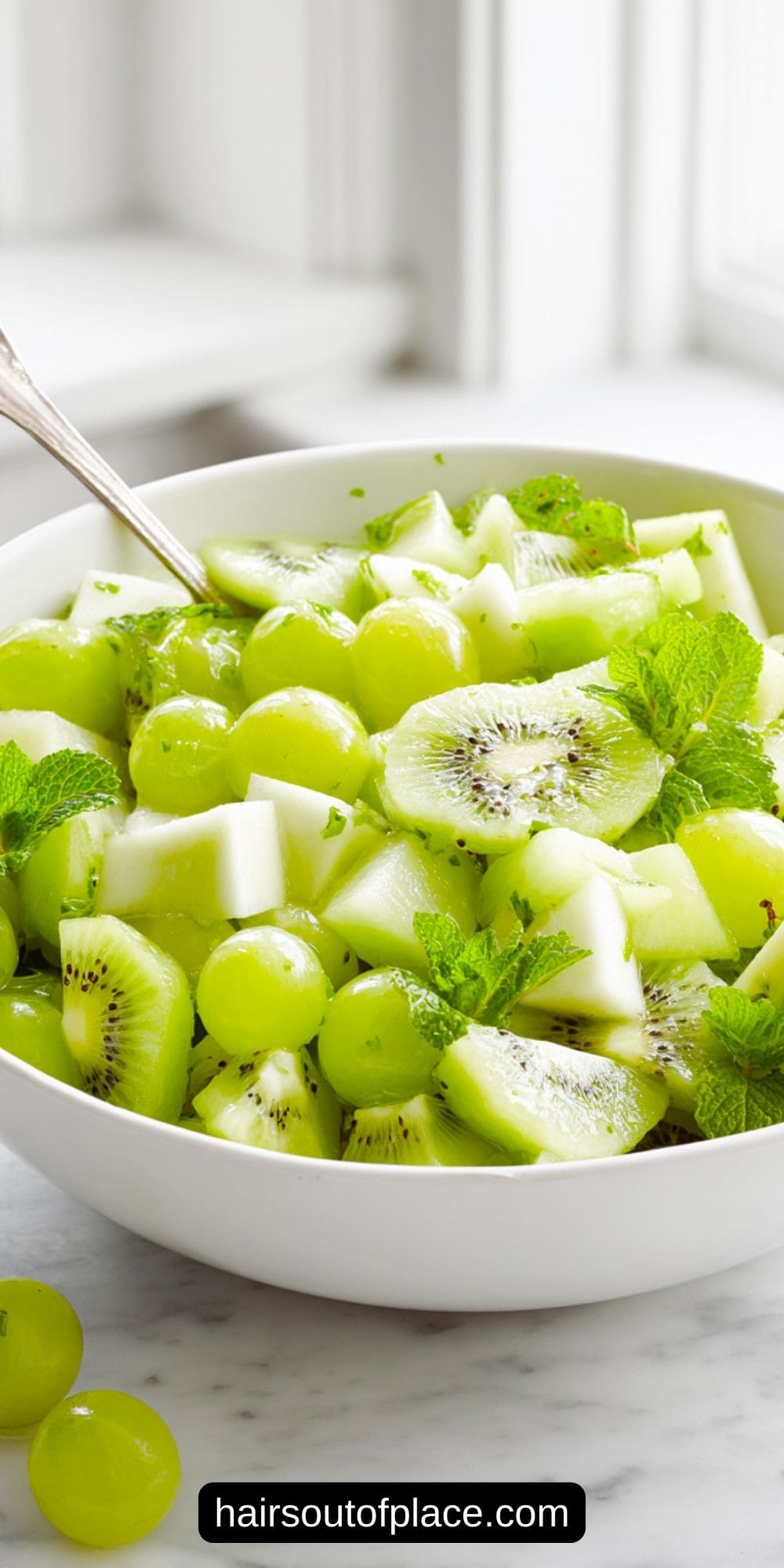 easy green fruit salad in a white bowl on a white counter
