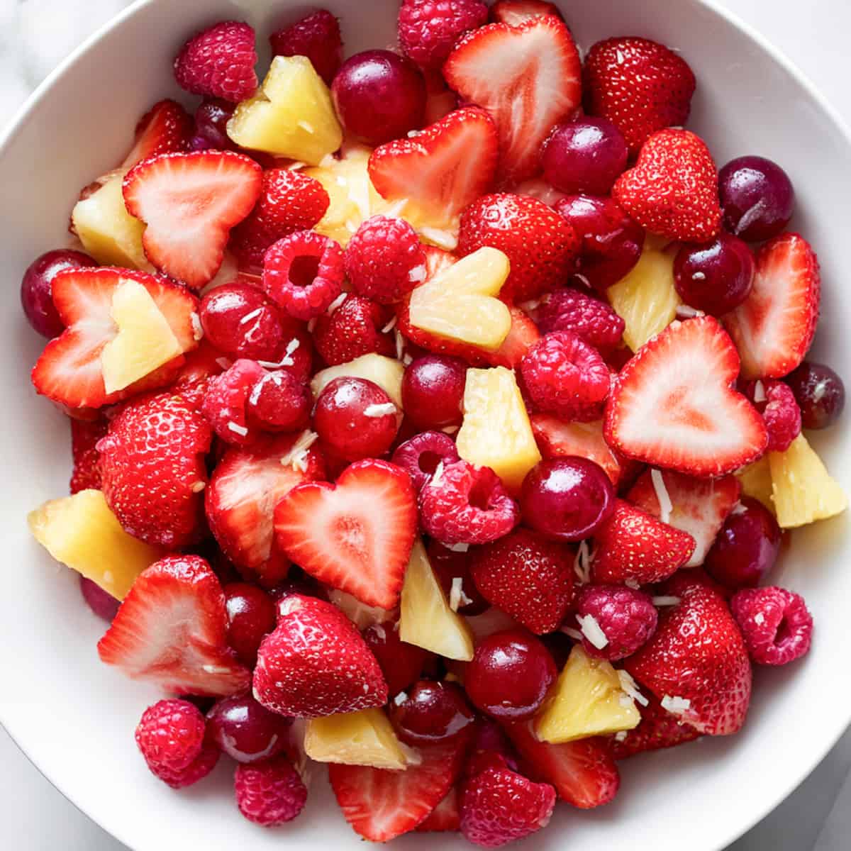 easy valentines fruit salad with strawberry hearts in a white bowl