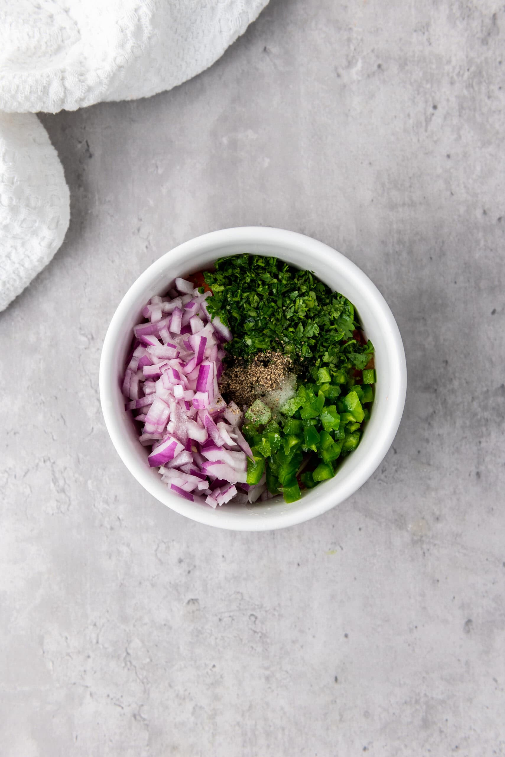 image showing ingredients for salsa being mixed together in a white bowl