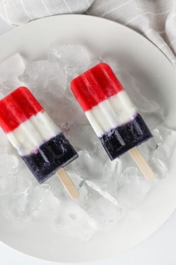 red white and blue yogurt popsicles sitting on ice to keep cold.