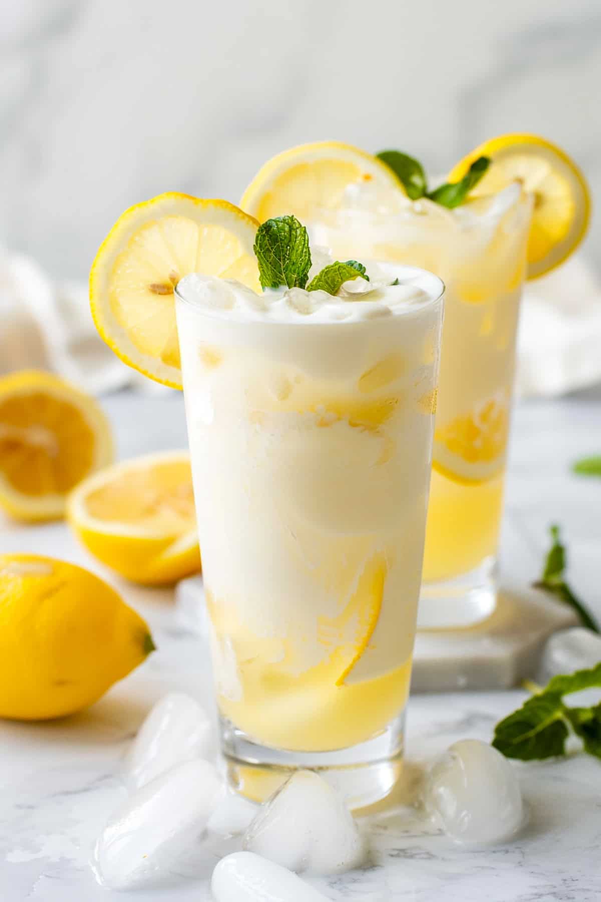 lemon cream dirty soda with sprite garnished with mint and lemon slices on a marble counter