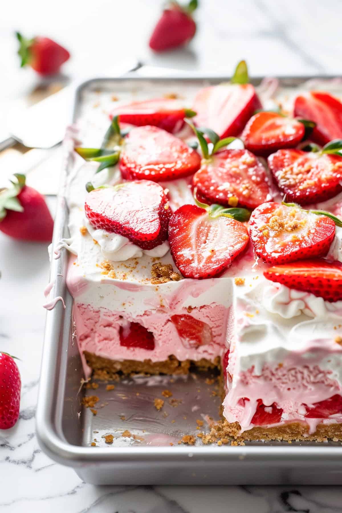 no bake strawberry ice cream cake in a pan with a slice cut out