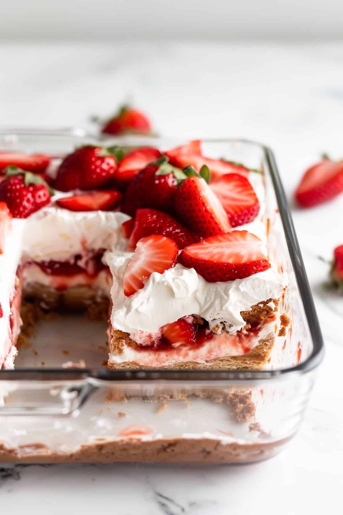 no bake strawberry tiramisu in a clear glass baking dish on a white background