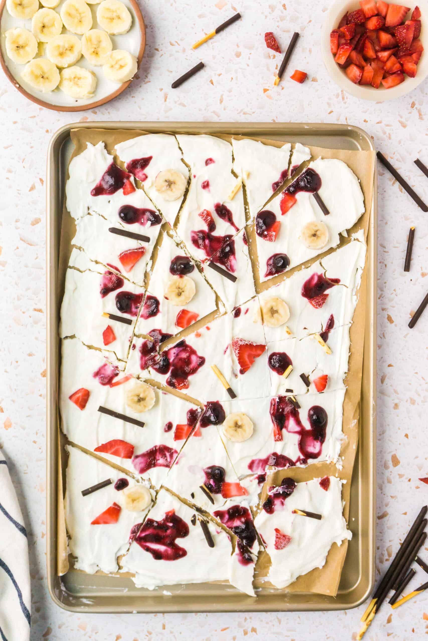 frozen yogurt bark recipe with berries jam banana and chocolate on a cooke sheet