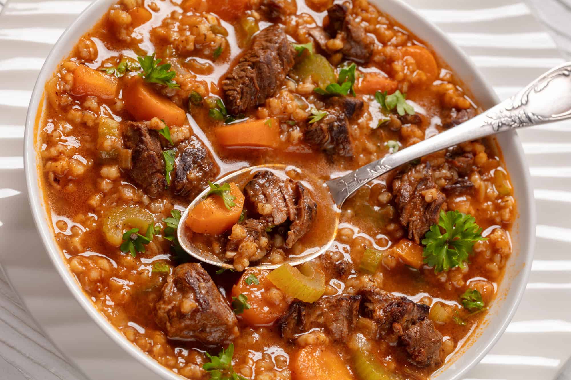 beef barley soup in a slow cooker in a white bowl