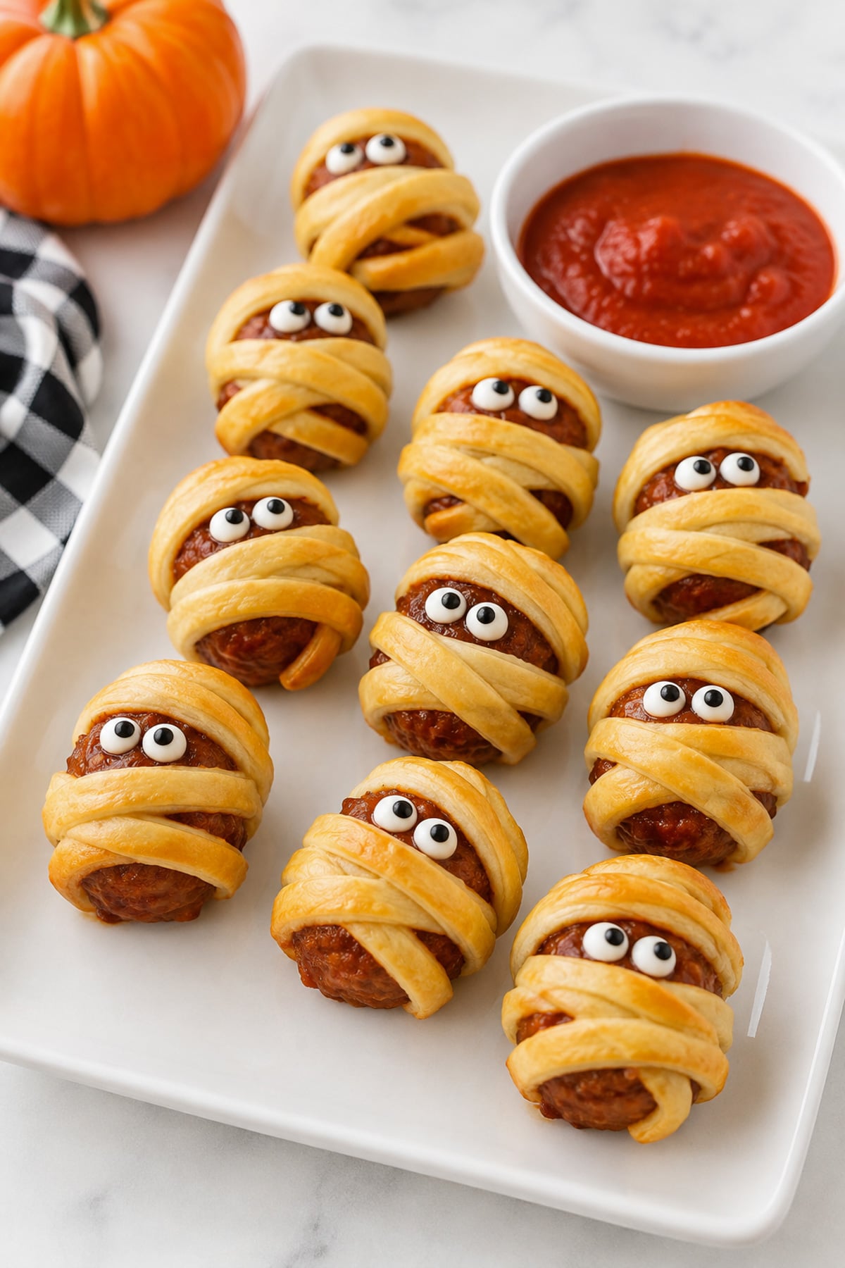 mummy meatballs wrapped in crescent rolls and with candy eyeballs for a halloween party