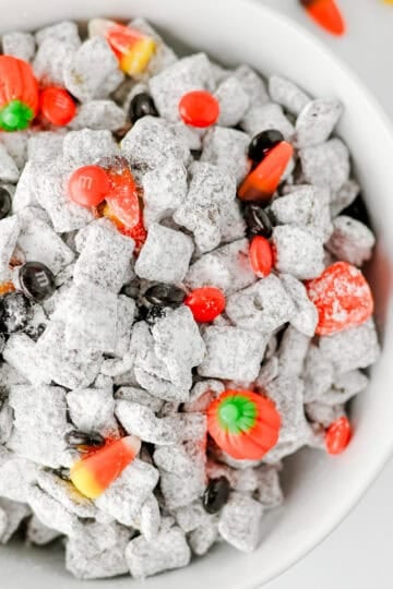 how to make easy muddy buddies for halloween, featured in a white bowl on a white background